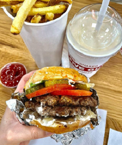 Top view of someone holding a Burger, fries and milkshake at Five Guys Sydney CBD