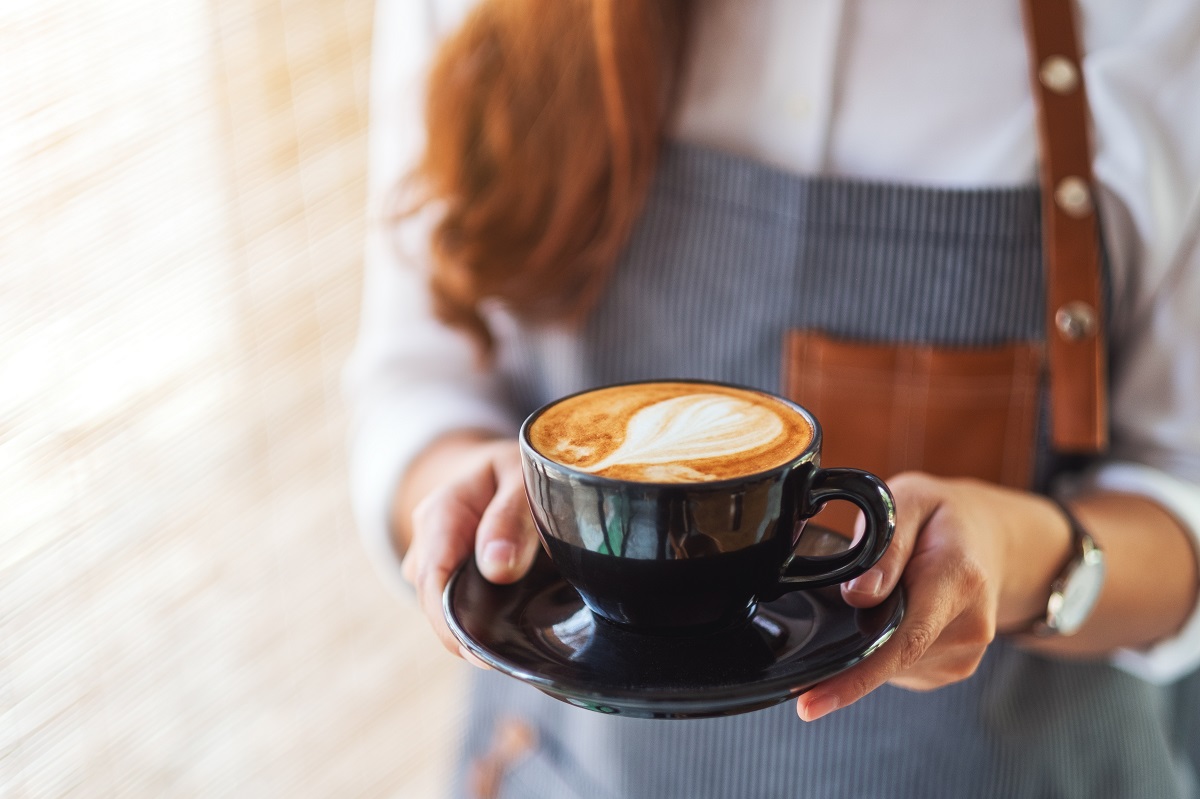 A waitress holding and serving a cup of hot coffee in cafe